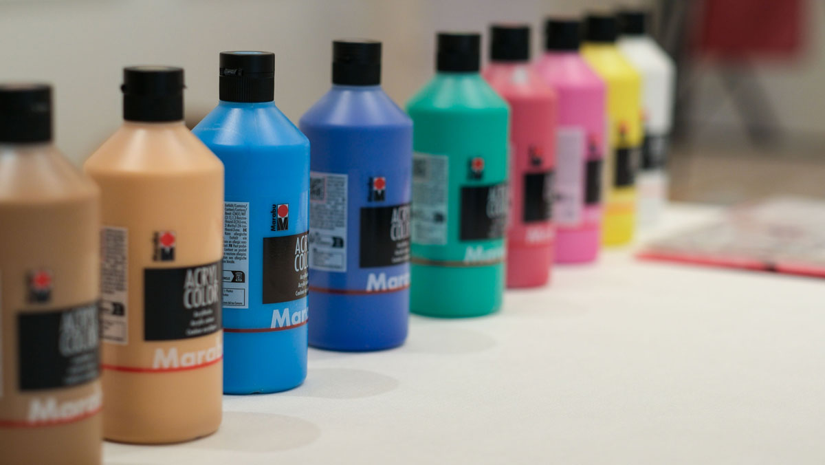 Verschiedene Flaschen mut Acrylfarbe stehen auf einem Tisch