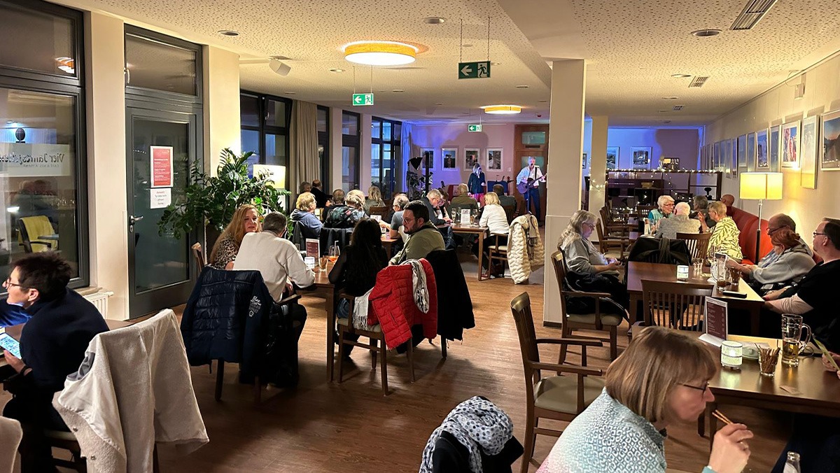 The „Vier Jahreszeiten“ restaurant in the ProCurand Bölschestraße senior citizens' residence: guests sit at tables, chat and enjoy the pub party together in a cosy atmosphere.