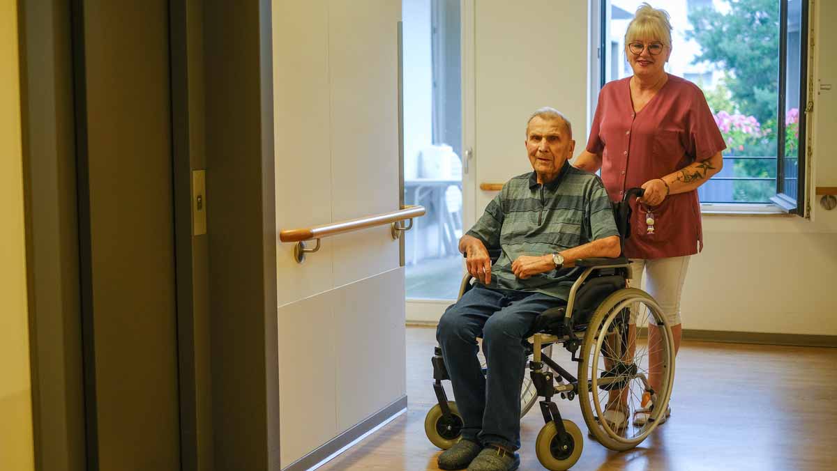Senior im Rollstuhl mit Pflegehelferin in der Stationären Pflege der Seniorenresidenz Bölschestraße