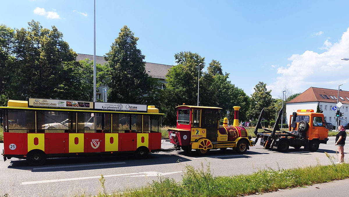 Kolleg*innen und Senior*innen der Seniorenresidenz Cottbus schauen der Bimmelbahn zu, wie sie abgeschleppt wird
