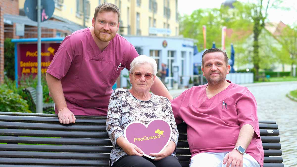 Bewohnerin mit zwei Pflegehelfern vor der Stationären Pflege der Seniorenresidenz Am Schlosspark