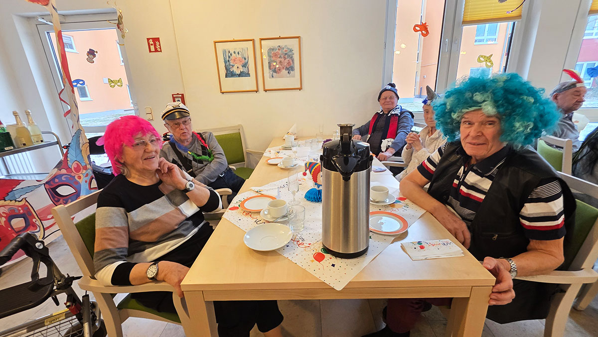 **Picture:** Carnival celebration at the ProCurand Eberswalde care home: Costumed residents sit together at a table, enjoying snacks and celebrating merrily.