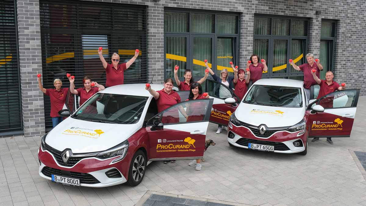 Team Ambulante Pflege Halle mit ProCurand-Herzen neben zwei ProCurand-Autos