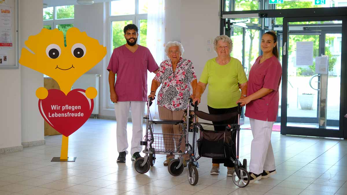 Zwei Seniorinnen stehen gemeinsam mit zwei Betreuer*innen stehen im Eingang der Stationären Pflege der Seniorenresidenz Am Hufeisensee