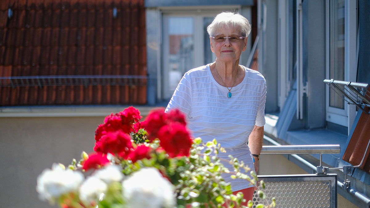 Eine Seniorin steht auf ihrem Balkon in der Stationären Pflege der Seniorenresidenz Park Sanssouci