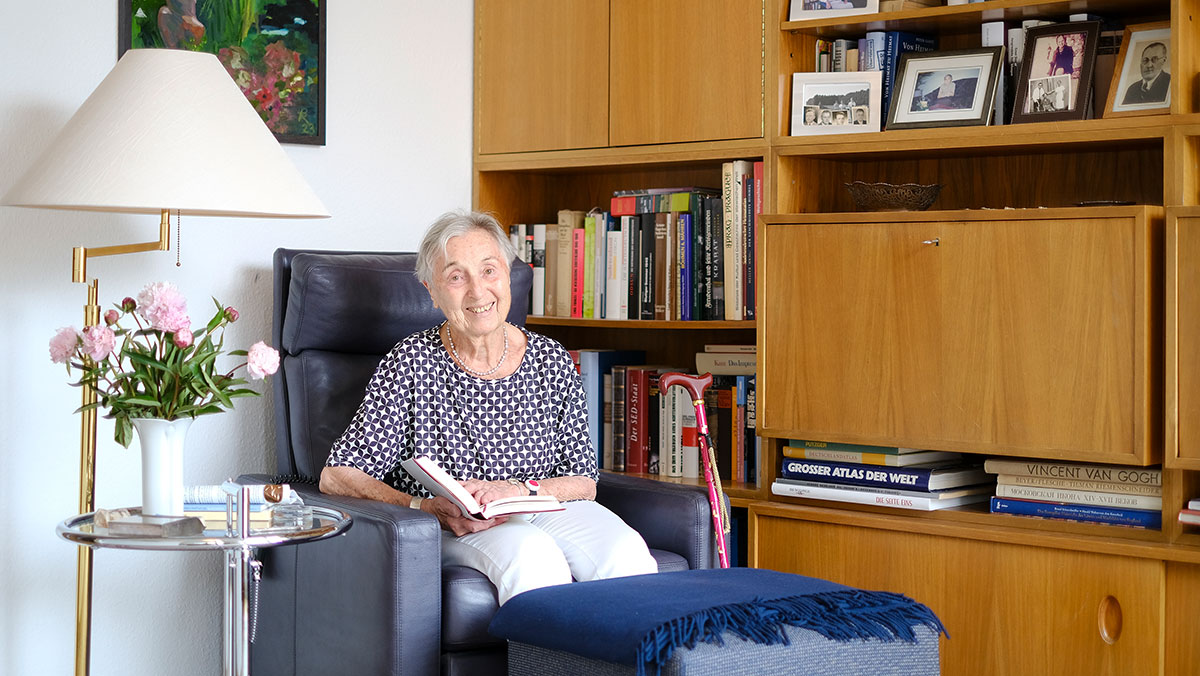 Eine Seniorin liest in ihrem Wohnzimmer in der Stationären Pflege der Seniorenresidenz Park Sanssouci