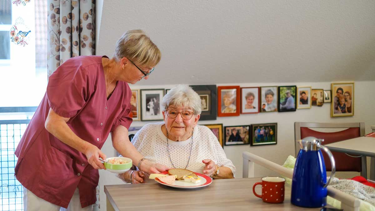 Eine Seniorin bekommt Verpflegung von einer Pflegekraft der Stationären Pflege Nächst Neuendorf