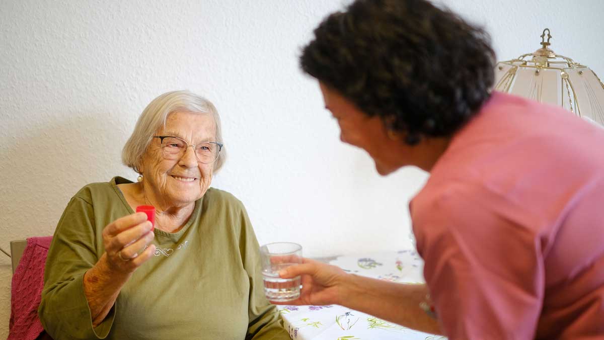 Seniorin bekommt Medikamente von einer Pflegekraft der Stationären Pflege Nächst Neuendorf